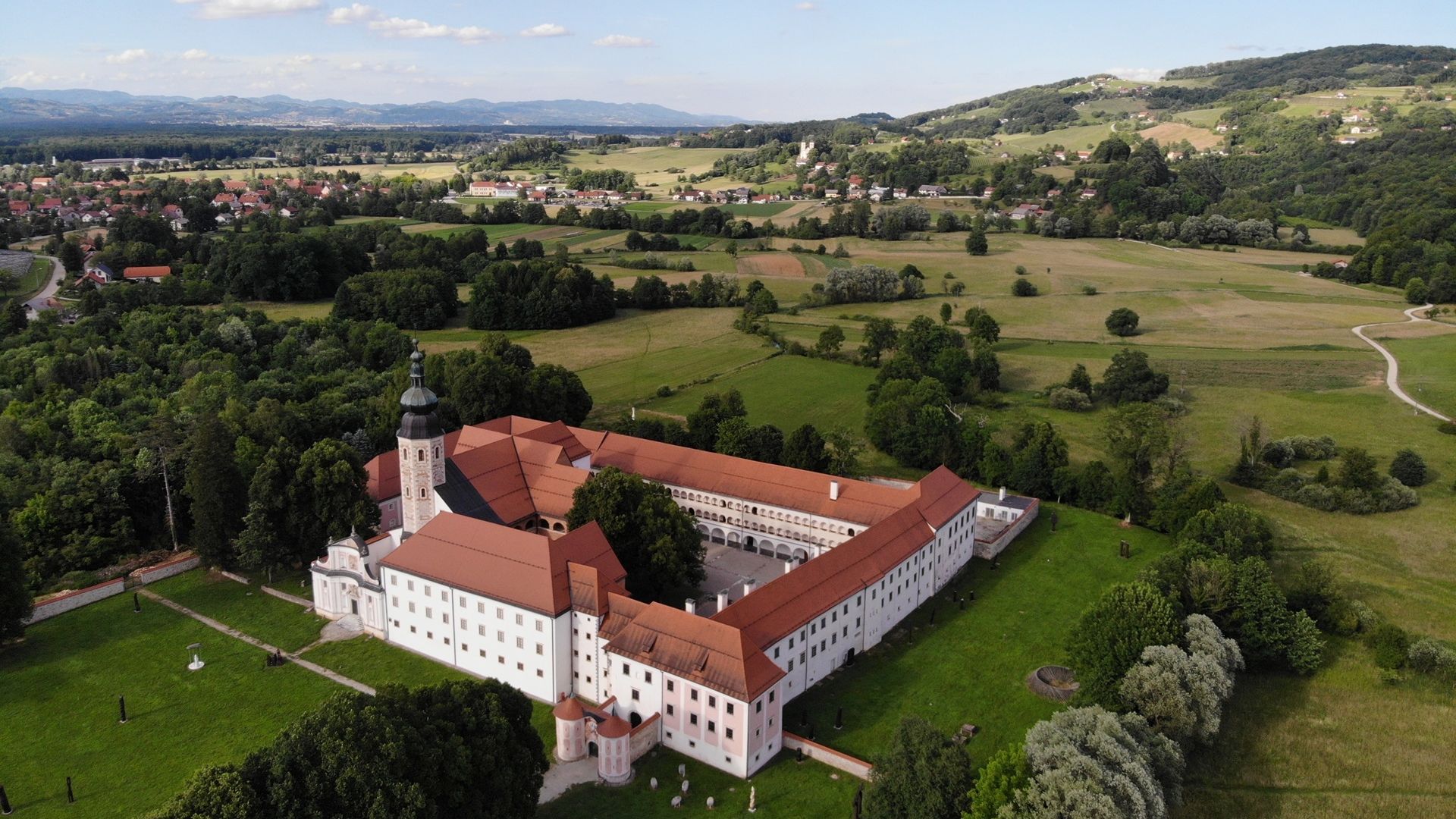 Fotografija gradu Kostanjevica na Krki, posneta iz zraka, obdanega z zeleno pokrajino.