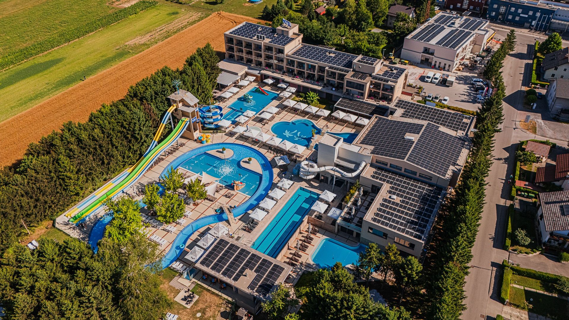 Fotografija bazena z dvema barvitima toboganoma, posneta iz zraka.