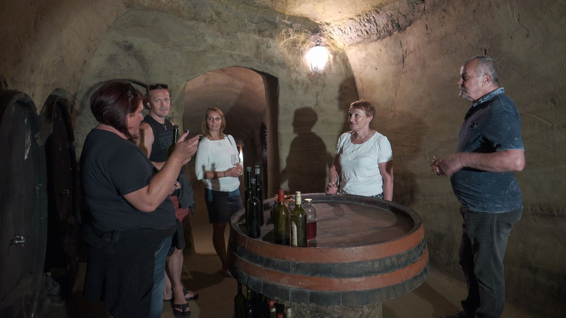 Fotografija petih ljudi, ki se pogovarjajo okoli soda.